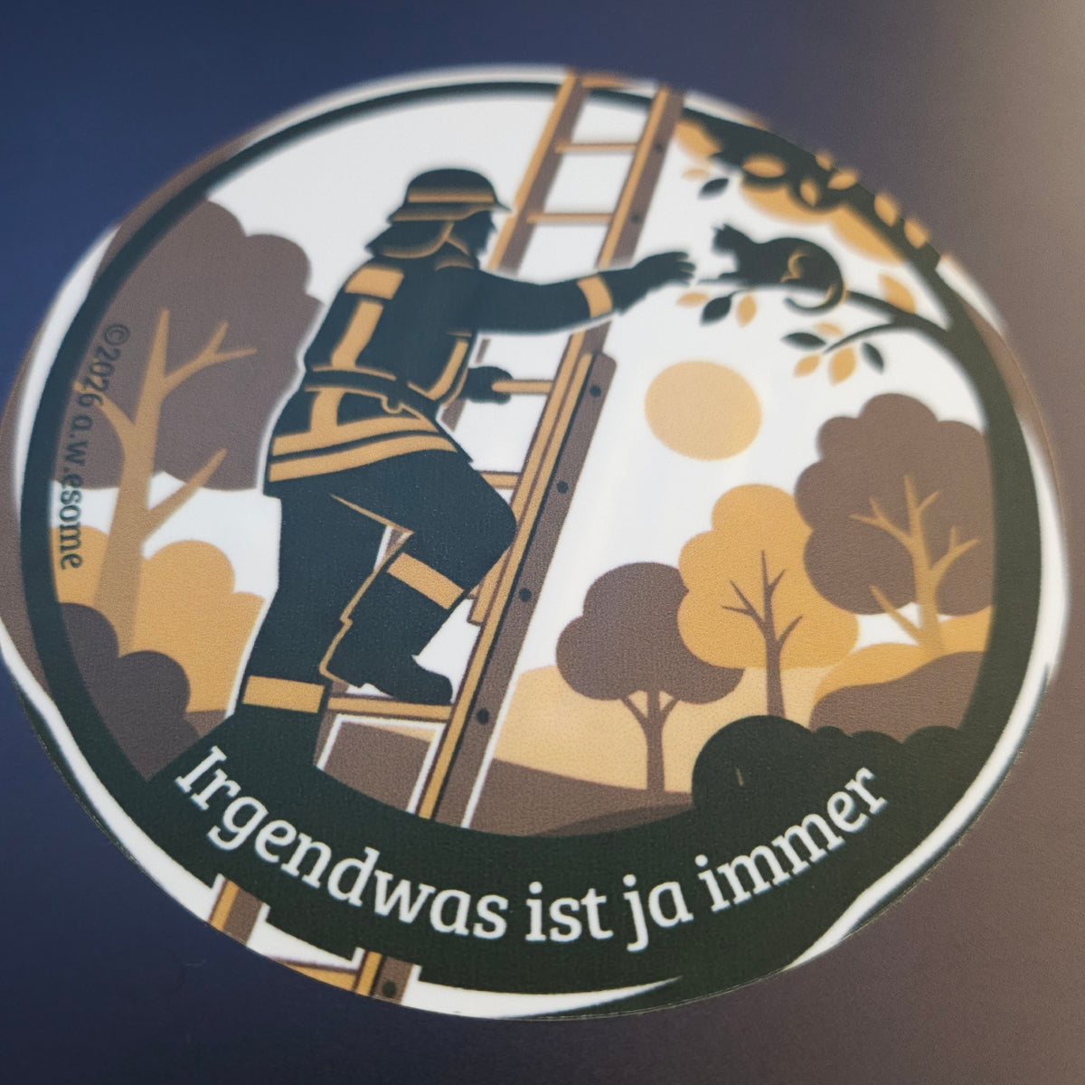 Runder Feuerwehr-Sticker aufgeklebt auf einer dunklen Oberfläche im kontrastreichen Wachen-Design.
