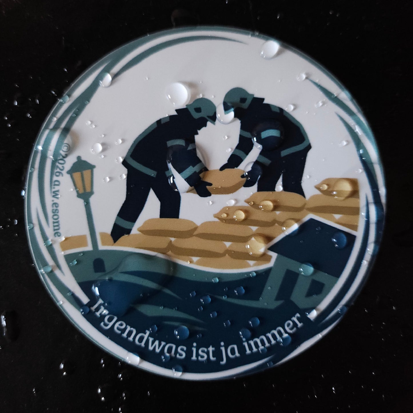 Nahaufnahme eines wasserfesten Feuerwehr-Stickers mit Wassertropfen auf der matten, wetterbeständigen Oberfläche.
