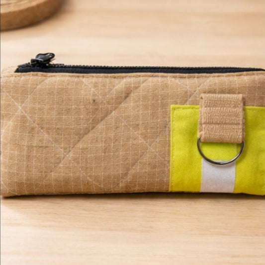 Nahaufnahme der kleinen Upcycling-Feuerwehrtasche mit neongelbem Reflektorband, silbernem D-Ring und robuster Stoffschlaufe.