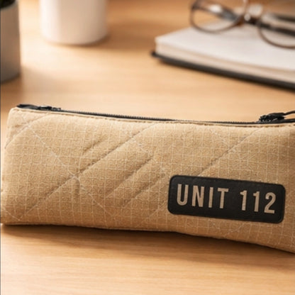 Längliche beige Federtasche UNIT 112 aus original Feuerwehr-Einsatzkleidung mit schwarzem Reißverschluss auf hellem Holzhintergrund.