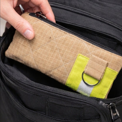 Ein beiges UNIT 112 Gear-Bag aus Upcycling-Material wird in das Hauptfach eines schwarzen Rucksacks gesteckt.