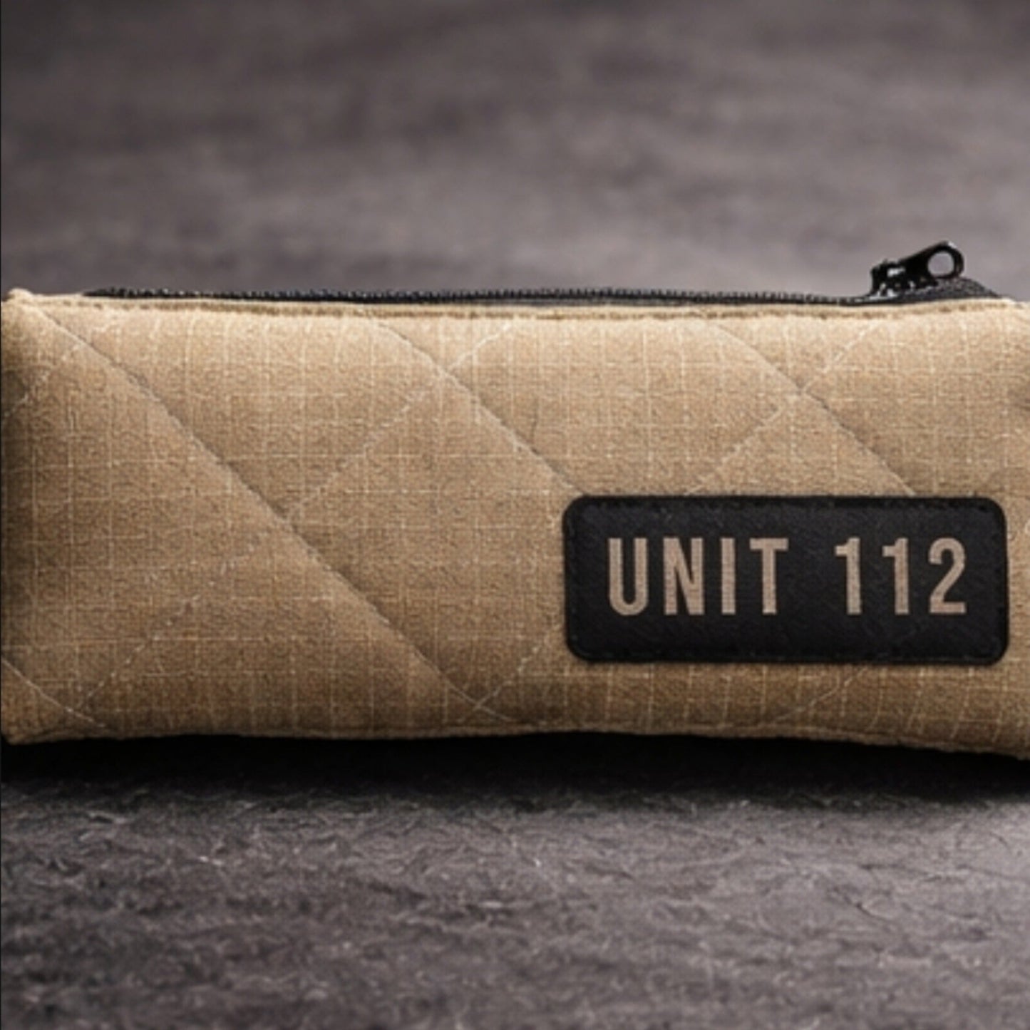 Kompaktes Werkzeugetui UNIT 112 aus beigem, gestepptem Feuerwehr-Material, platziert auf einem Schreibtisch.