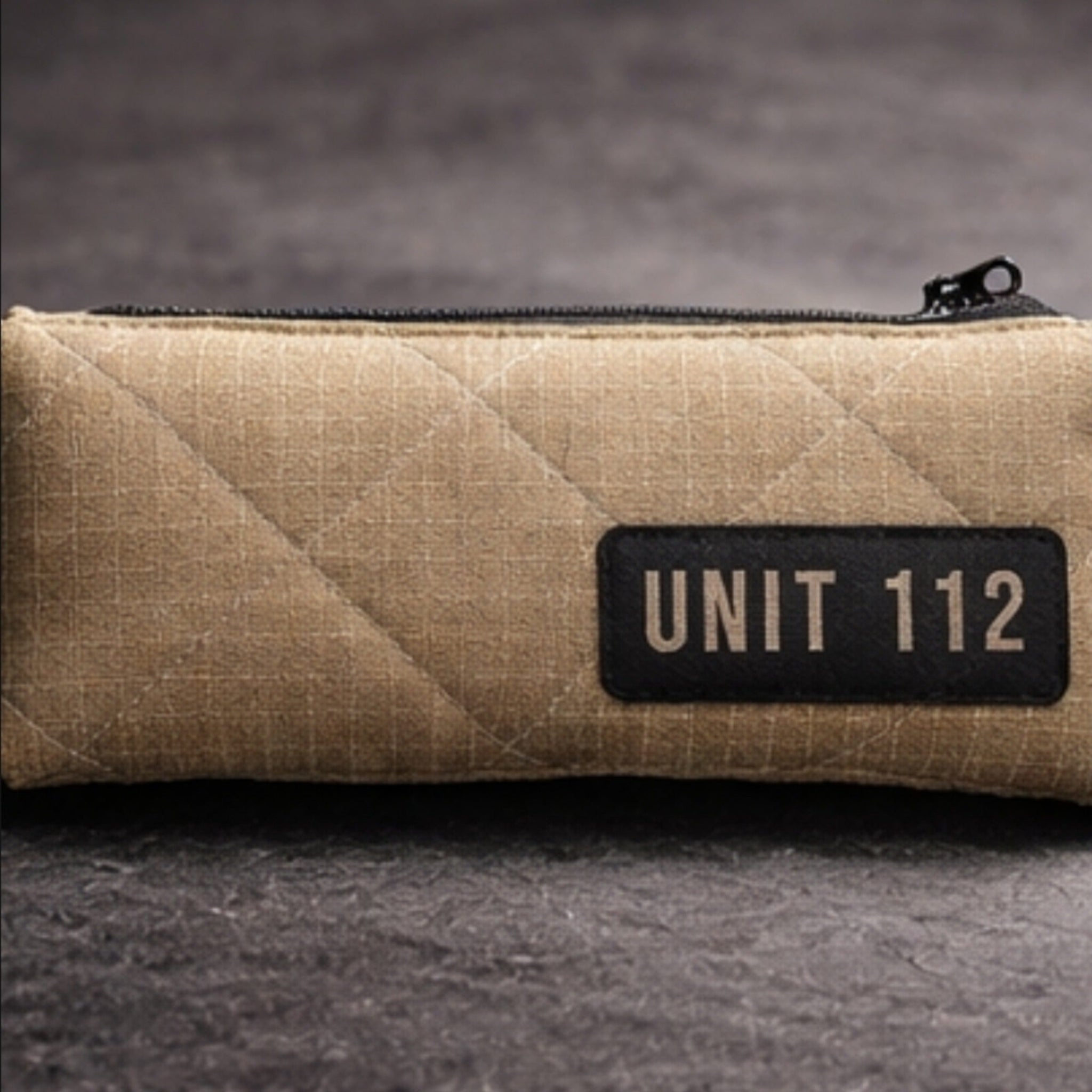 Kompaktes Werkzeugetui UNIT 112 aus beigem, gestepptem Feuerwehr-Material, platziert auf einem Schreibtisch.