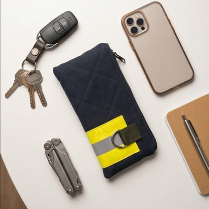 Ästhetische Draufsicht auf die Upcycling-Tasche umgeben von Alltagsgegenständen wie Autoschlüssel, iPhone, Taschenmesser und Notizbuch.