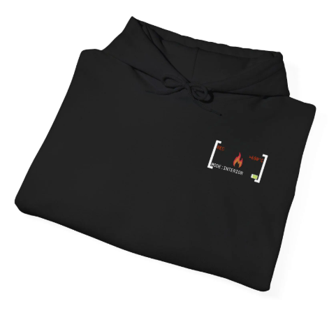 Ordentlich zusammengefalteter schwarzer Feuerwehr-Hoodie auf Holzgrund, der das dezente Brustlogo im Detail zeigt.