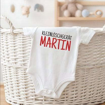 Personalisierter Baby-Strampler mit rotem Namensaufdruck Martin hängt dekorativ an einem weißen geflochtenen Wäschekorb.