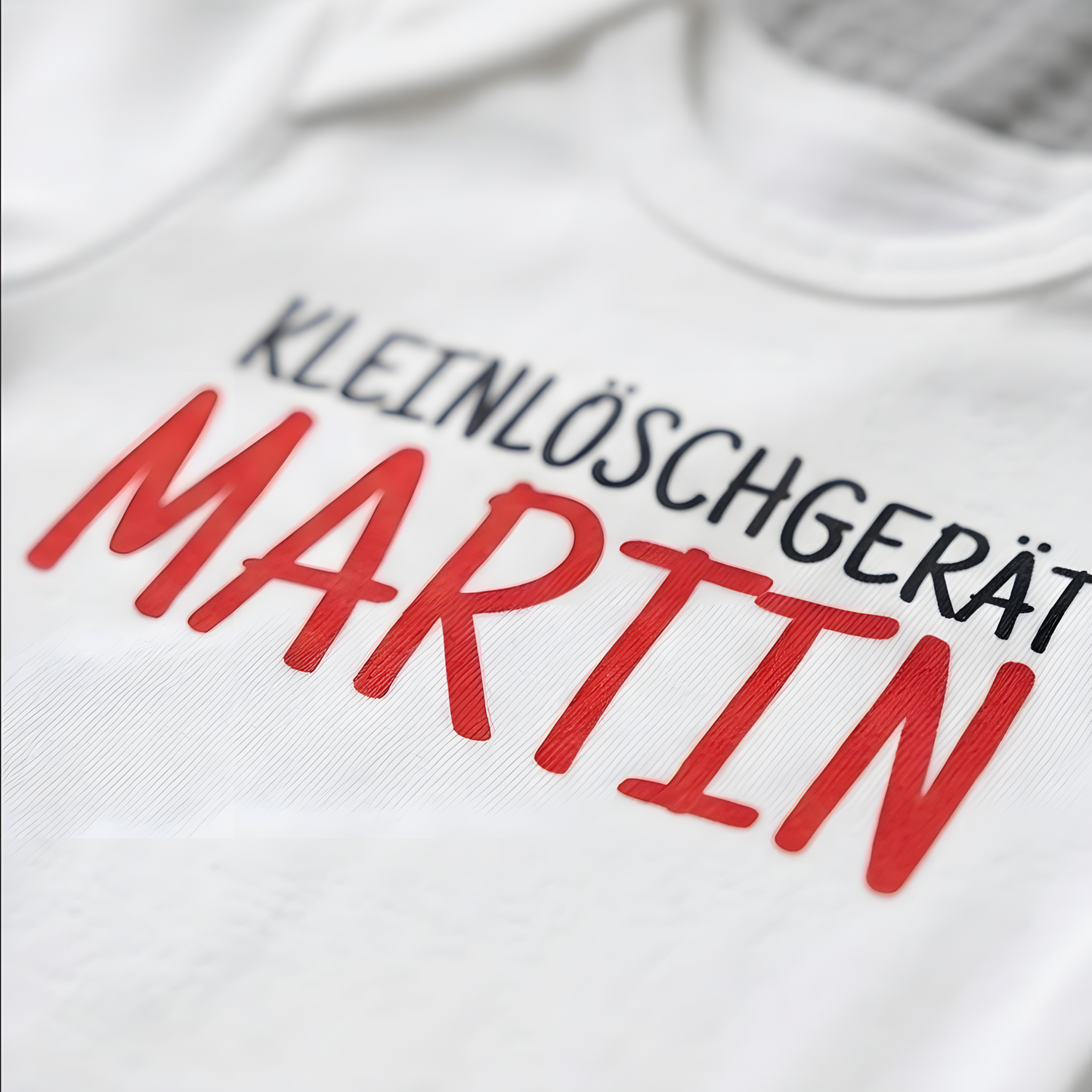Detailansicht des hochwertigen und speichelfesten Foliendrucks Kleinlöschgerät Martin auf dem weißen Stoff.
