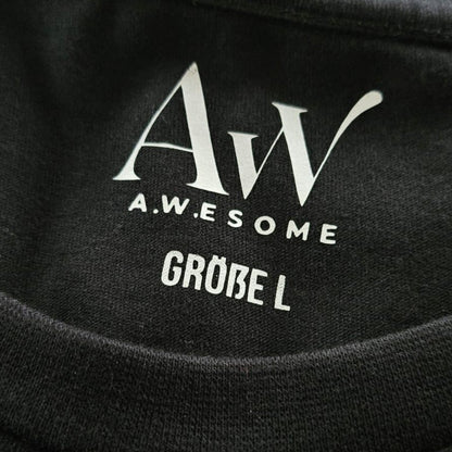 Detail des Nackenbereichs beim schwarzen Pullover mit eingedrucktem weißen AW Awesome Markenlogo und der Größenangabe.