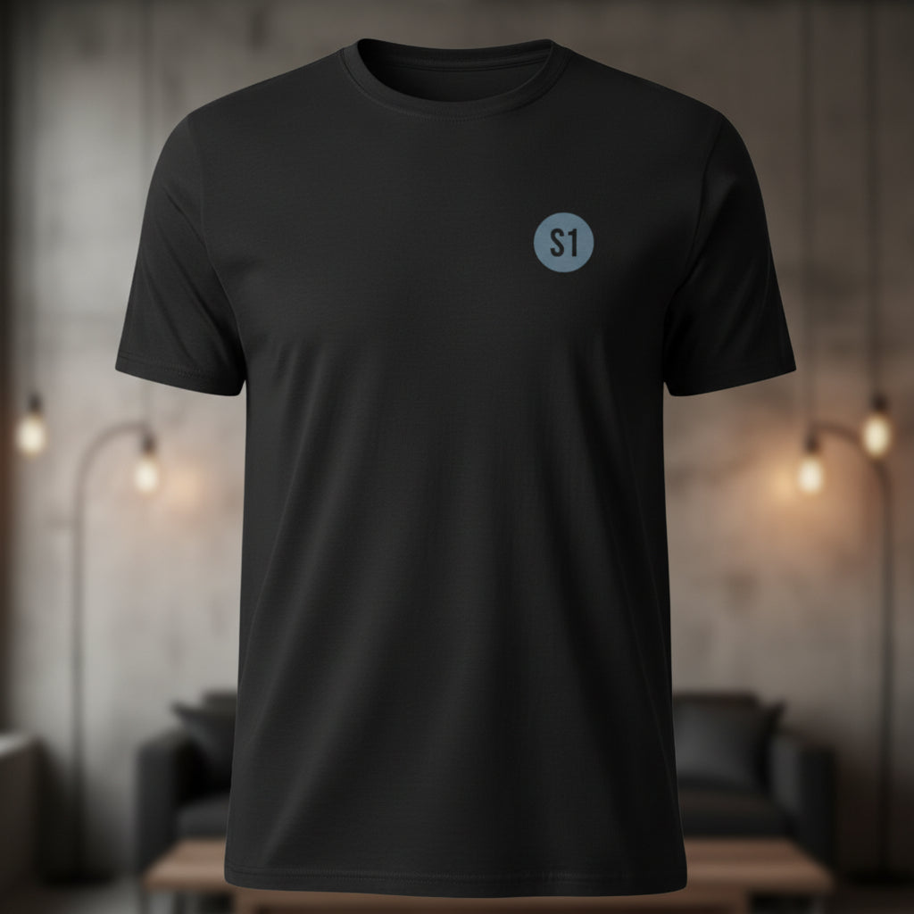 Vorderansicht des schwarzen Unisex T-Shirts im Regular Fit mit einem kleinen, runden Status-1-Logo auf der linken Brust.