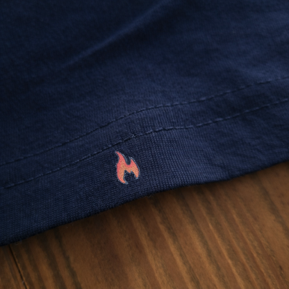 Nahaufnahme einer kleinen roten Flamme, die auf den Saum des navy-blauen Feuerwehr-THL-Shirts gedruckt ist.