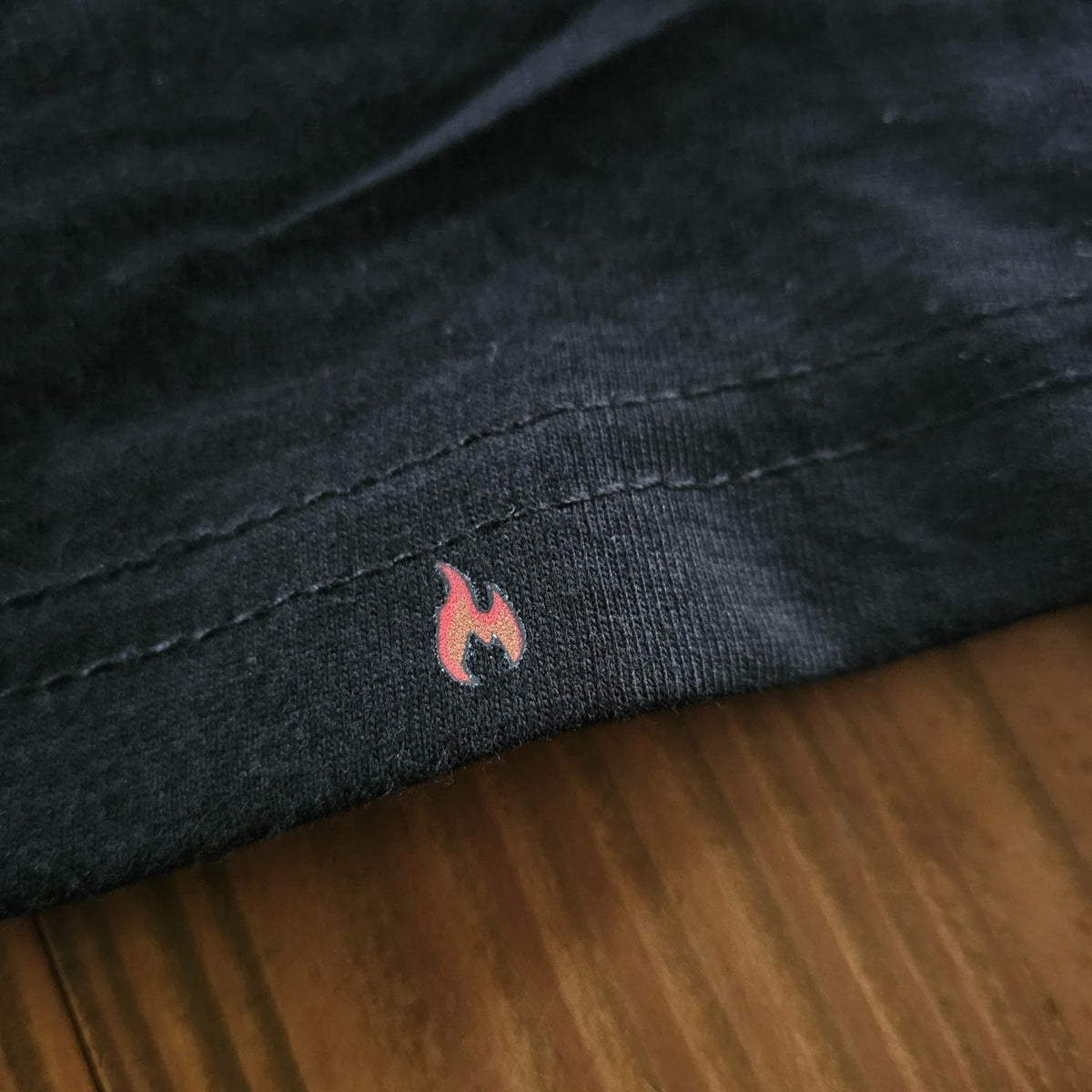Feuerwehr T-Shirt Innenangriff schwarz – Nahaufnahme Flammen-Logo am Saum