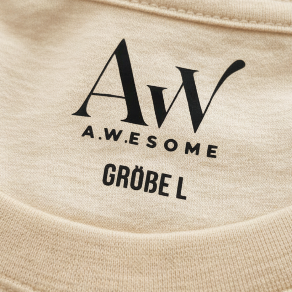 Detail des Nackenbereichs beim sandfarbenen Pullover mit eingedrucktem schwarzen AW Awesome Markenlogo und der Größenangabe.