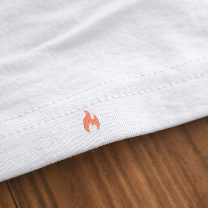 Nahaufnahme des unteren Saums vom weißen Feuerwehr-T-Shirt mit einer dezent eingedruckten, kleinen roten Flamme auf Holz.