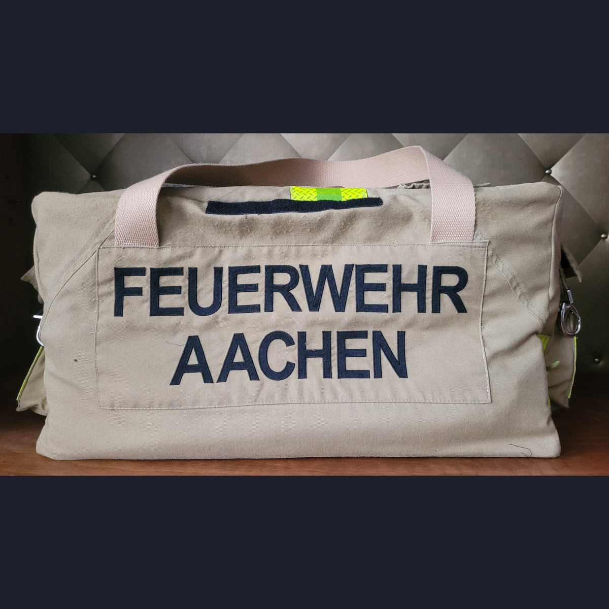Upcycling-Feuerwehrtasche aus beiger Feuerwehrjacke mit dunkelblauem Aufdruck FEUERWEHR AACHEN und hellen Tragegurten.