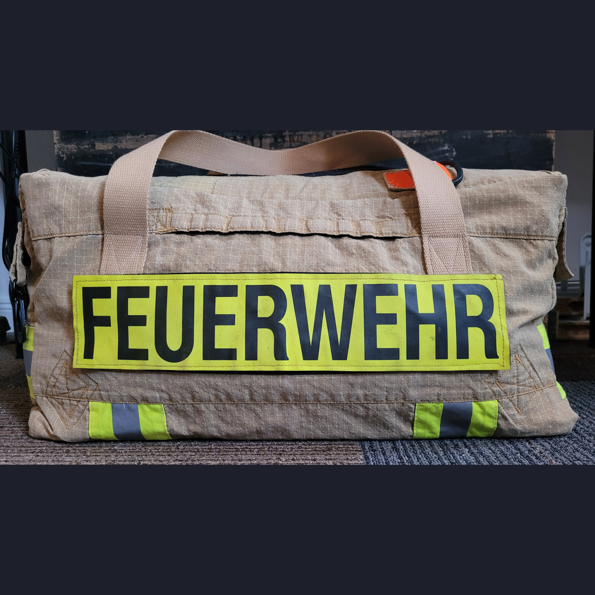 Personalisierte Upcycling-Feuerwehrtasche aus beiger Einsatzkleidung mit Tragegurten und großem gelben FEUERWEHR-Klettschild.