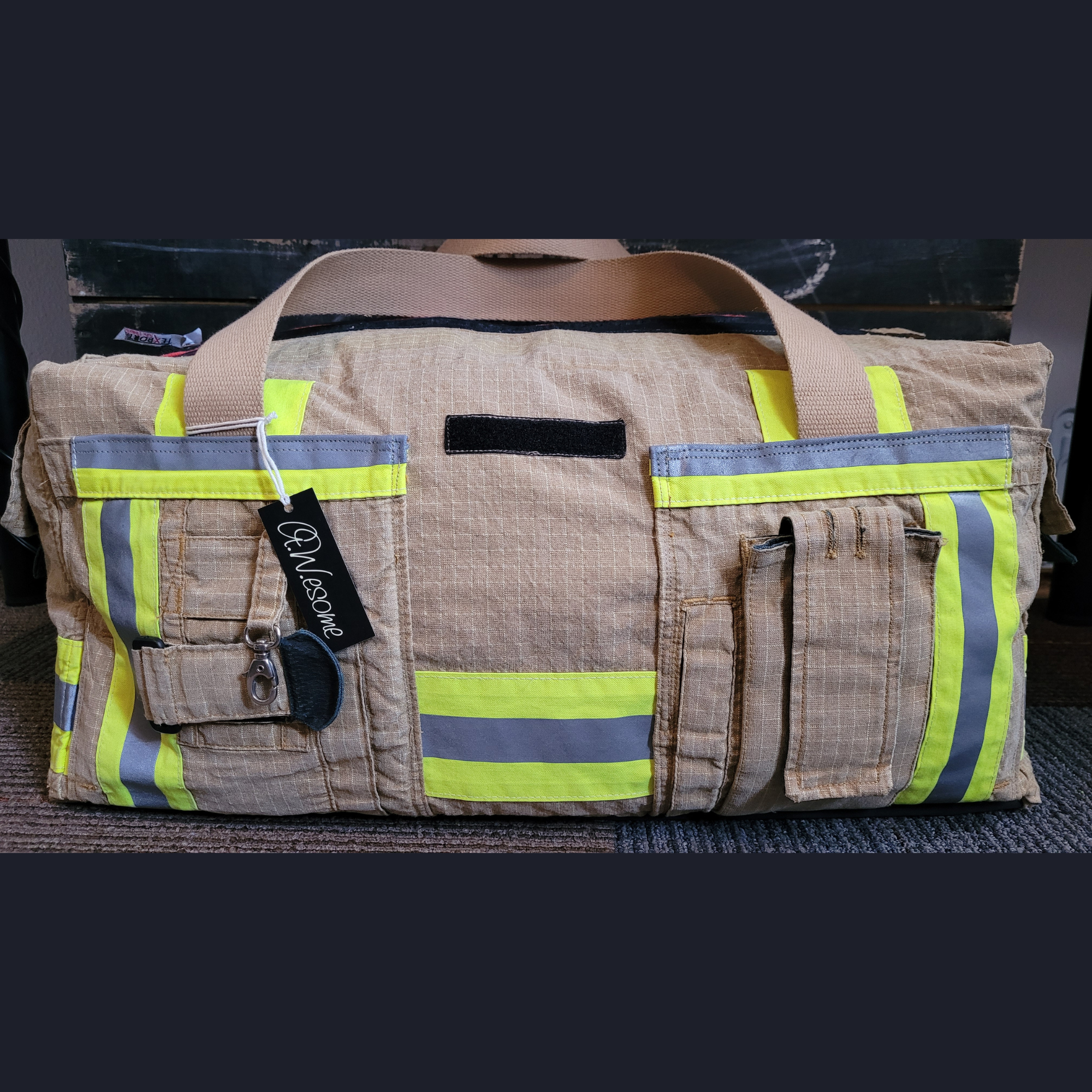 Upcycling-Feuerwehrtasche Rückansicht aus beiger Einsatzkleidung mit aufgesetzten Taschen, gelb-silbernen Reflektoren und A.W.esome-Markenanhänger.