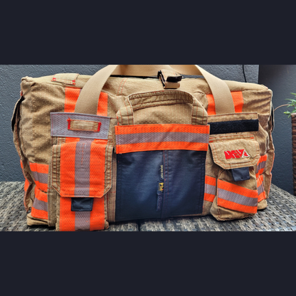Upcycling-Feuerwehrtasche aus beiger Einsatzkleidung mit orange-silbernen Reflektoren, aufgesetzten Taschen, Gore-Tex-Elementen und DEVA-Logo.