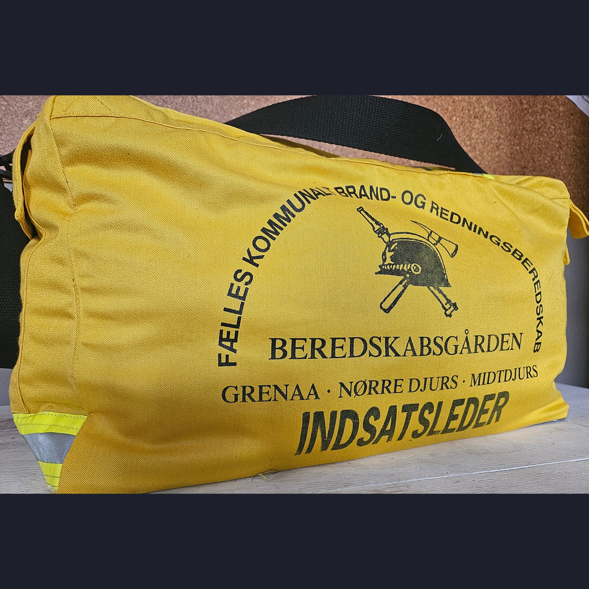 Upcycling-Feuerwehrtasche aus gelber Einsatzkleidung mit dänischem BEREDSKABSGÅRDEN INDSATSLEDER Rückenaufdruck und Helm-Logo.
