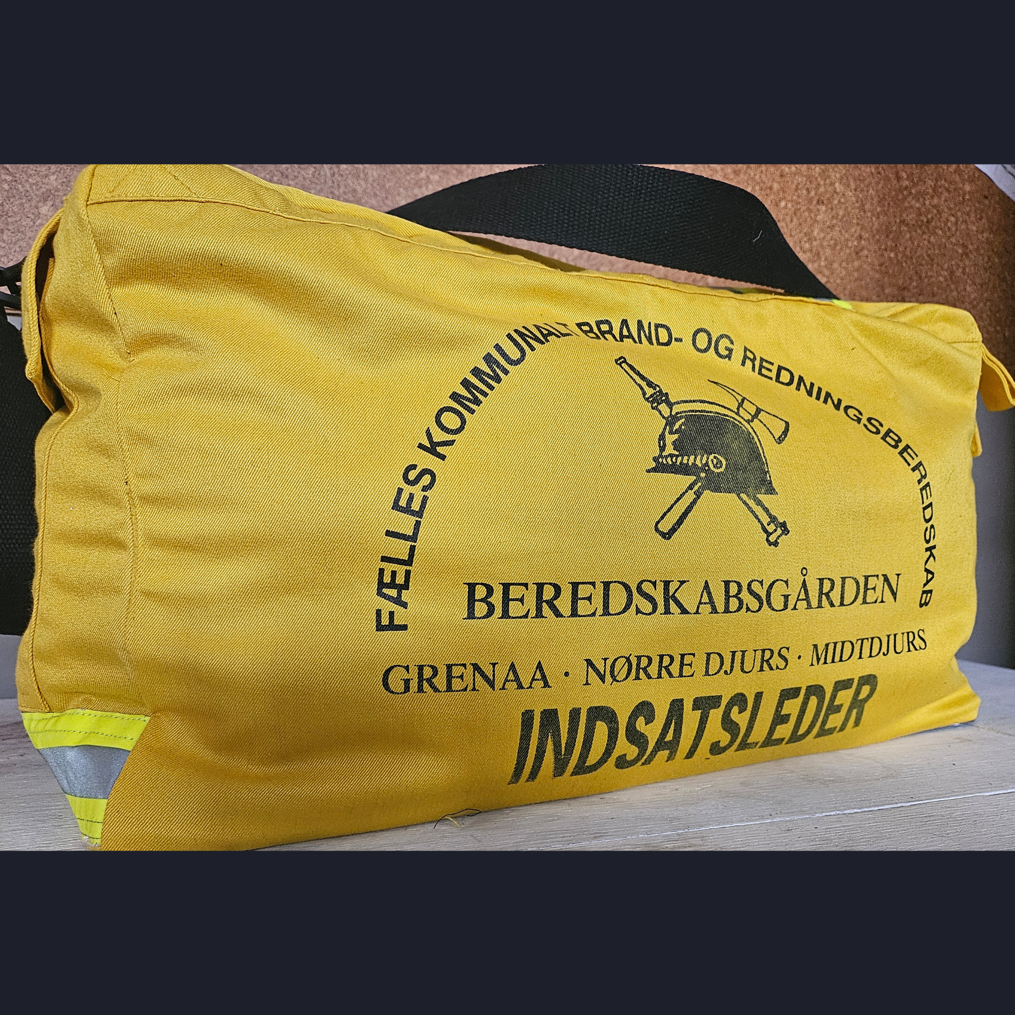 Upcycling-Feuerwehrtasche aus gelber Einsatzkleidung mit dänischem BEREDSKABSGÅRDEN INDSATSLEDER Rückenaufdruck und Helm-Logo.