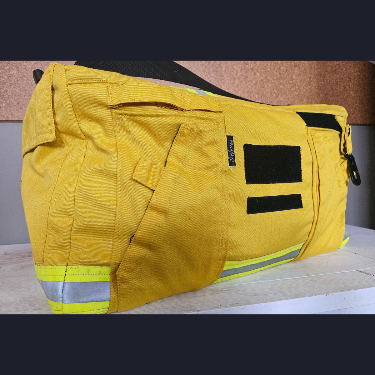 Upcycling-Feuerwehrtasche aus gelber Einsatzkleidung mit neongelben Reflektorstreifen, schrägen Einschubtaschen und schwarzen Klettstreifen.