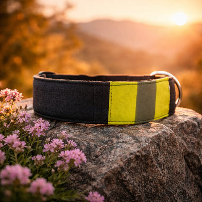 Robustes Feuerwehr Hundehalsband aus dunkelblauer Einsatzkleidung mit gelb-silbernem Reflexstreifen liegt auf einem Stein im Sonnenuntergang.