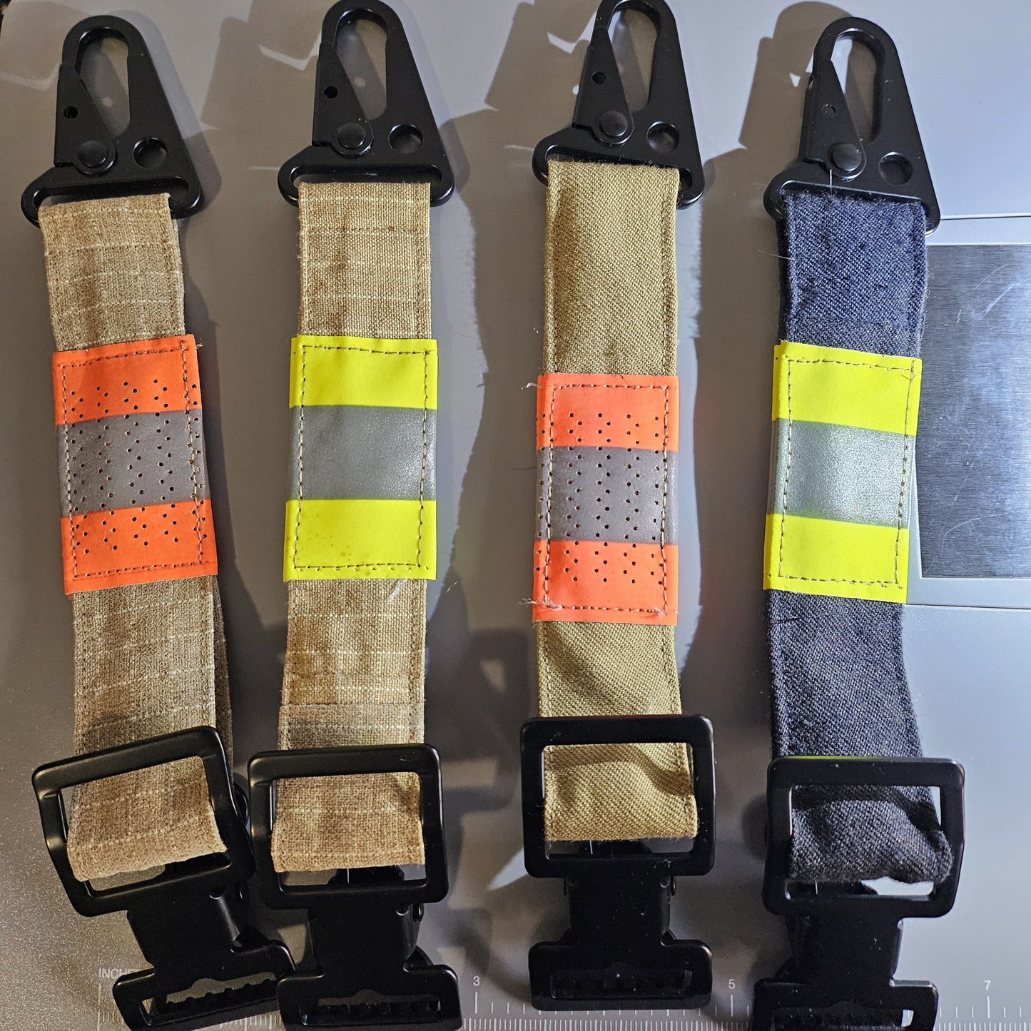 "Feuerwehr-Handschuhhalter mit Taktik-Karabiner in allen Varianten: sandfarben-kariert, sandfarben und dunkelblau mit orangen und gelben Reflexstreifen – Upcycling aus Aramid-Einsatzkleidung"