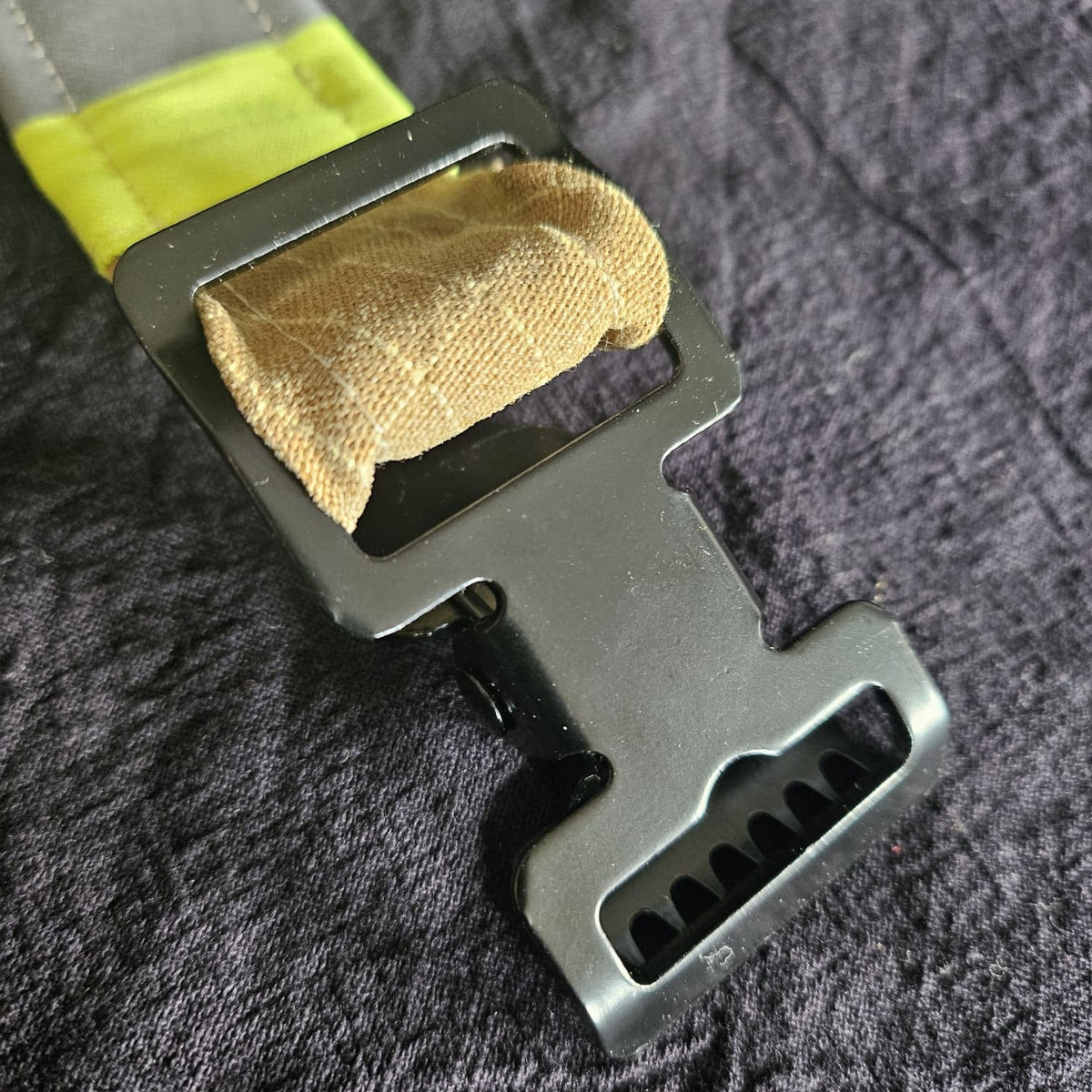 "Detailansicht des schwarzen Metall-Greifclips am sandfarbenen Feuerwehr-Handschuhhalter mit neongelben Reflexstreifen – Nahaufnahme der robusten Zinklegierungs-Schnalle"

