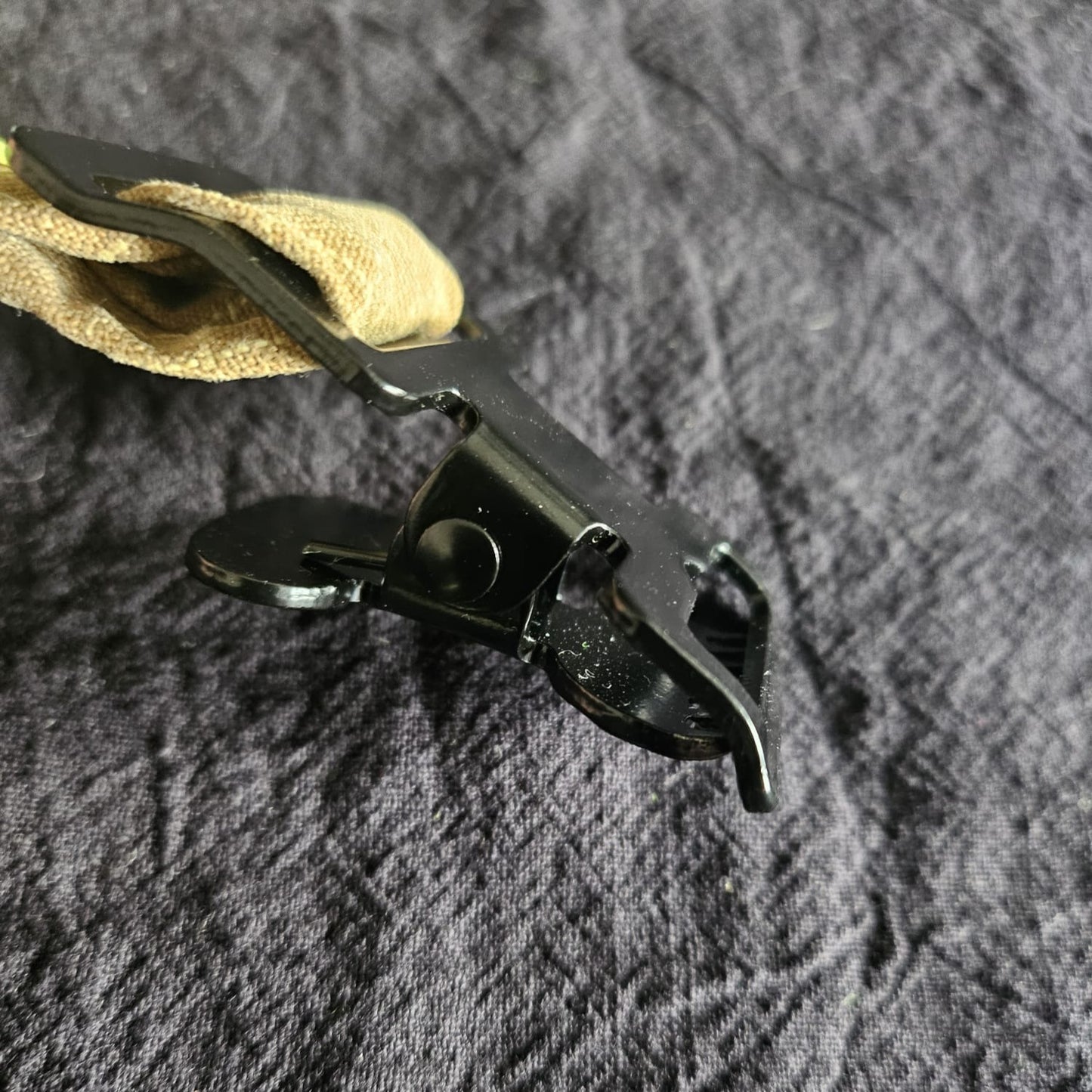 "Seitenansicht des schwarzen Scherenkarabiners am sandfarbenen Feuerwehr-Handschuhhalter – geschlossener Metallhaken aus Zinklegierung für die Technische Hilfeleistung"

