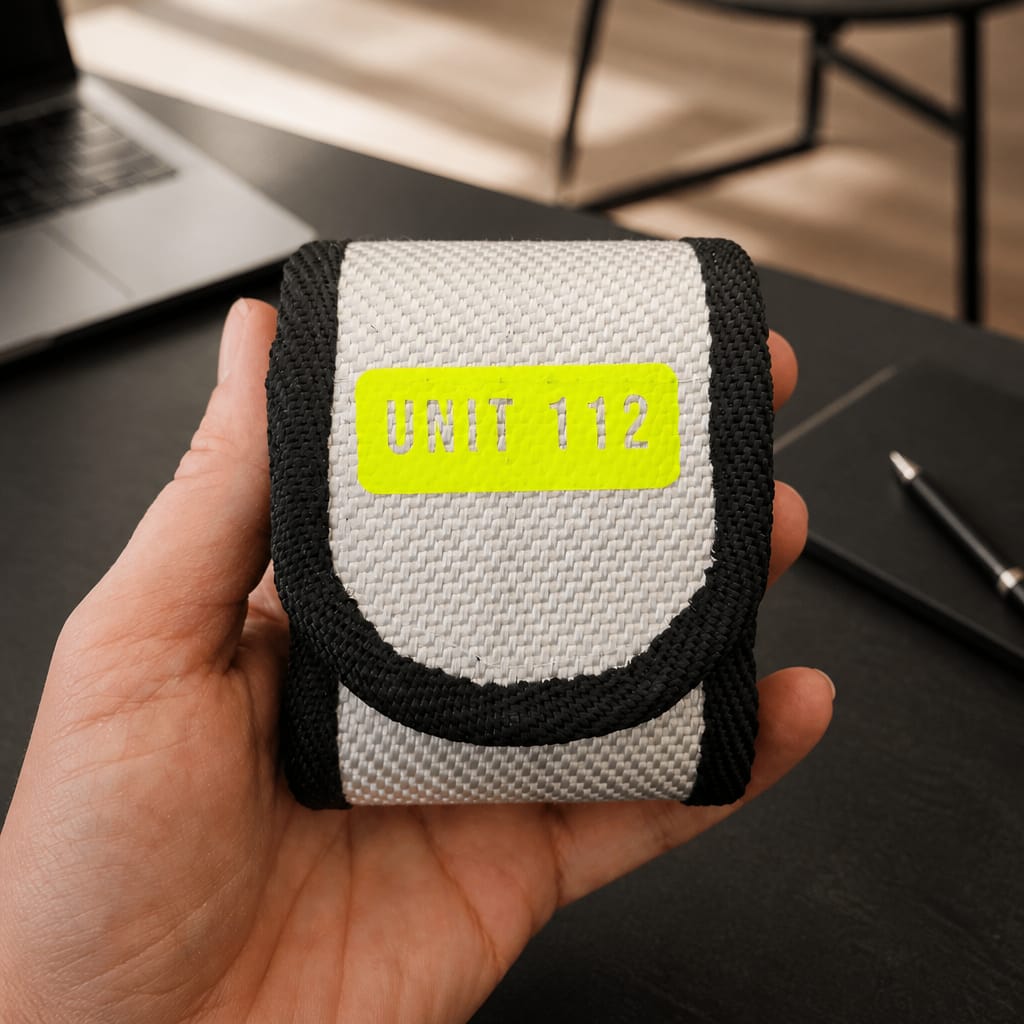"Frontansicht der Upcycling Meldertasche für Swissphone s.QUAD aus weißem Feuerwehrschlauch mit neongelben UNIT 112 Print"