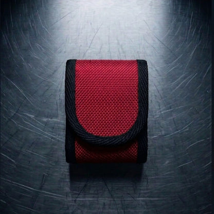 "Rote Upcycling Meldertasche für Swissphone s.QUAD aus Feuerwehrschlauch mit schwarzer Gurtband-Einfassung – Frontansicht auf Metalluntergrund"