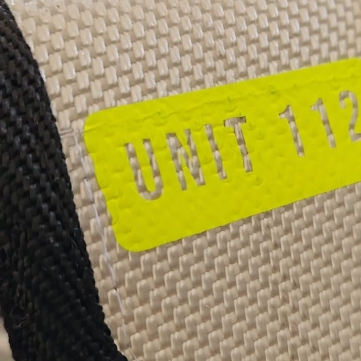 "Nahaufnahme des neongelben UNIT 112 Flexfolien-Prints auf weißem Feuerwehrschlauch-Gewebe der Upcycling Meldertasche – hochwertige Veredelung im Detail"