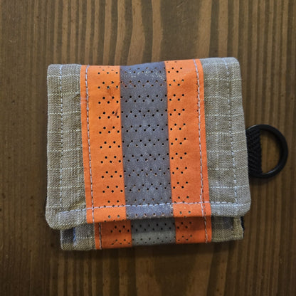 "Feuerwehr Mini-Notfall-Tasche sandfarben kariert mit orangenem Reflexstreifen – Draufsicht auf Holzuntergrund, schwarzer D-Ring seitlich"
