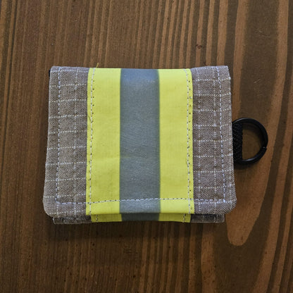 "Feuerwehr Mini-Notfall-Tasche sandfarben kariert mit gelbem Reflexstreifen – Draufsicht auf Holzuntergrund, schwarzer D-Ring seitlich"


