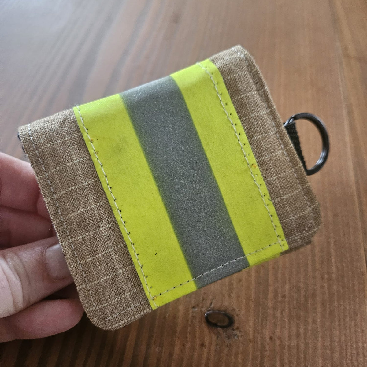 "Feuerwehr Mini-Notfall-Tasche sandfarben kariert mit gelbem Reflexstreifen – in der Hand gehalten, Größenvergleich"

