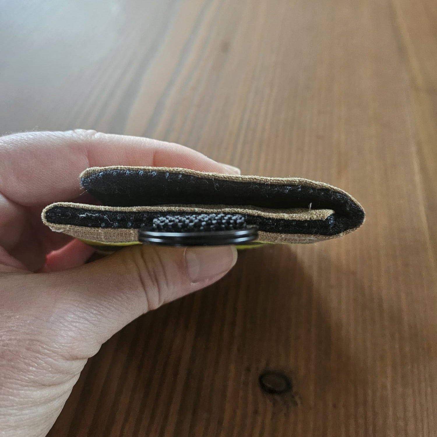 "Feuerwehr Mini-Notfall-Tasche sandfarben – Seitenansicht in der Hand, flache Bauweise ca. 1,5 cm, schwarzer Klettverschluss und D-Ring sichtbar"

