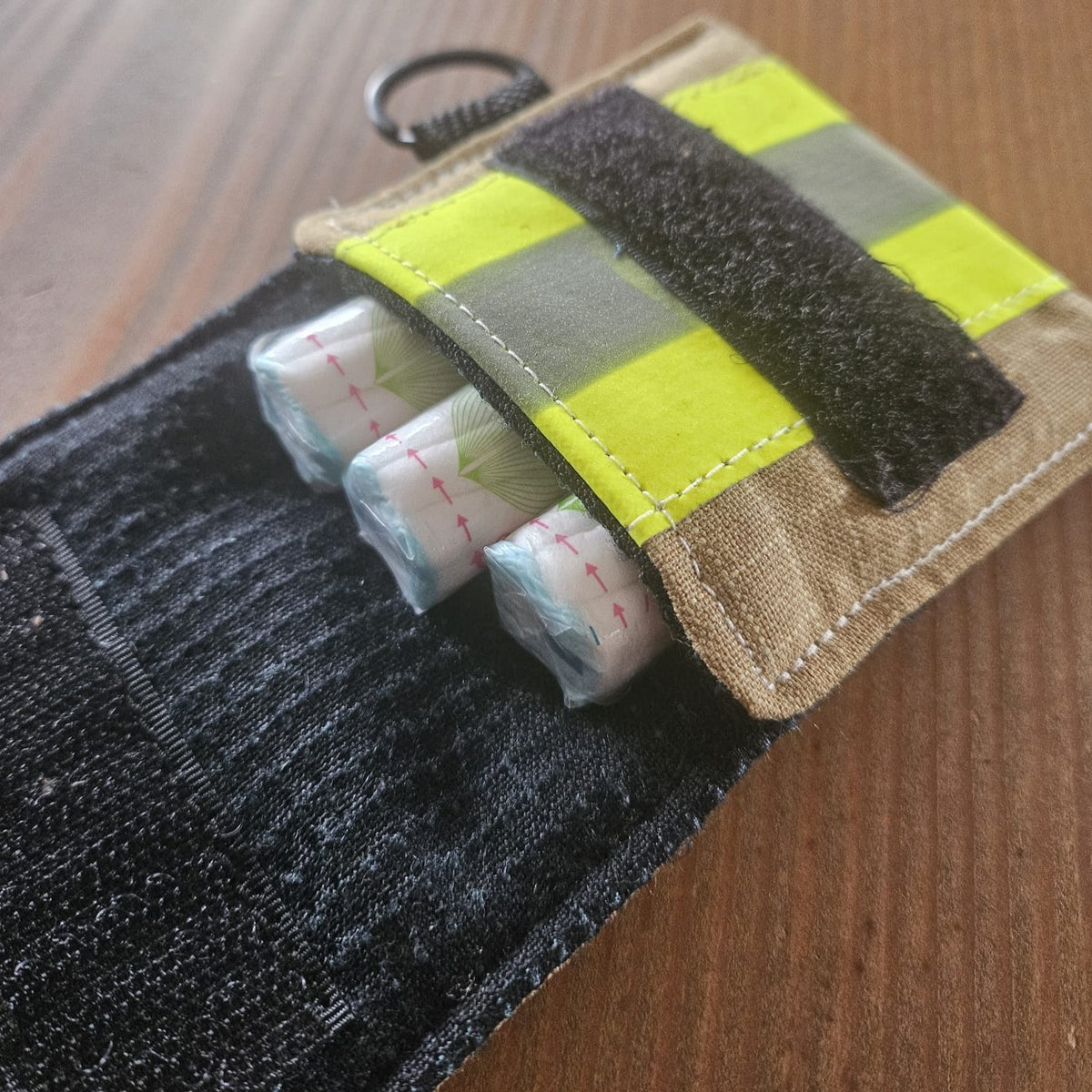 "Geöffnete Feuerwehr Mini-Notfall-Tasche sandfarben mit Hygieneartikel-Inhalt – als diskrete Hygienetasche für den Alltag, D-Ring oben sichtbar"

