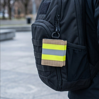 "Feuerwehr Mini-Notfall-Tasche sandfarben kariert mit gelbem Reflexstreifen – am Karabiner eines schwarzen Rucksacks befestigt"

