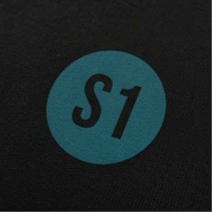 Detailansicht des runden, blau-grünen Brust-Aufdrucks mit dem Schriftzug S1 im minimalistischen Feuerwehr-Funkstatus-Design.