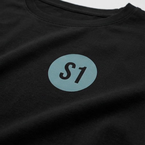 Detailansicht des runden, blau-grünen Funkstatus-Brustprints mit dem Schriftzug S1 im minimalistischen Feuerwehr-Design.