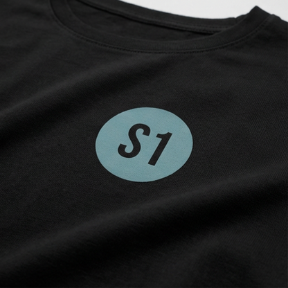 Detailansicht des runden, blau-grünen Funkstatus-Brustprints mit dem Schriftzug S1 im minimalistischen Feuerwehr-Design.